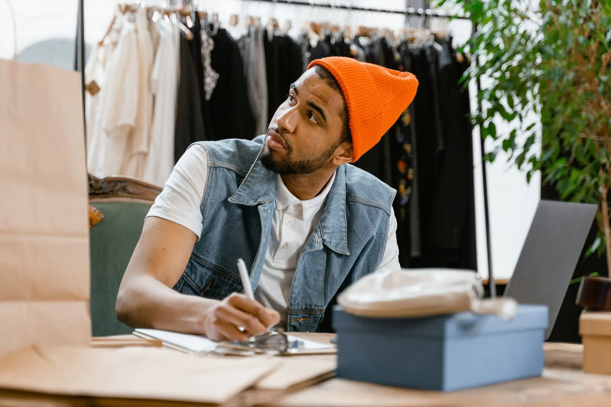 Clothing boutique owner working through the numbers on a notepad at the shop counter